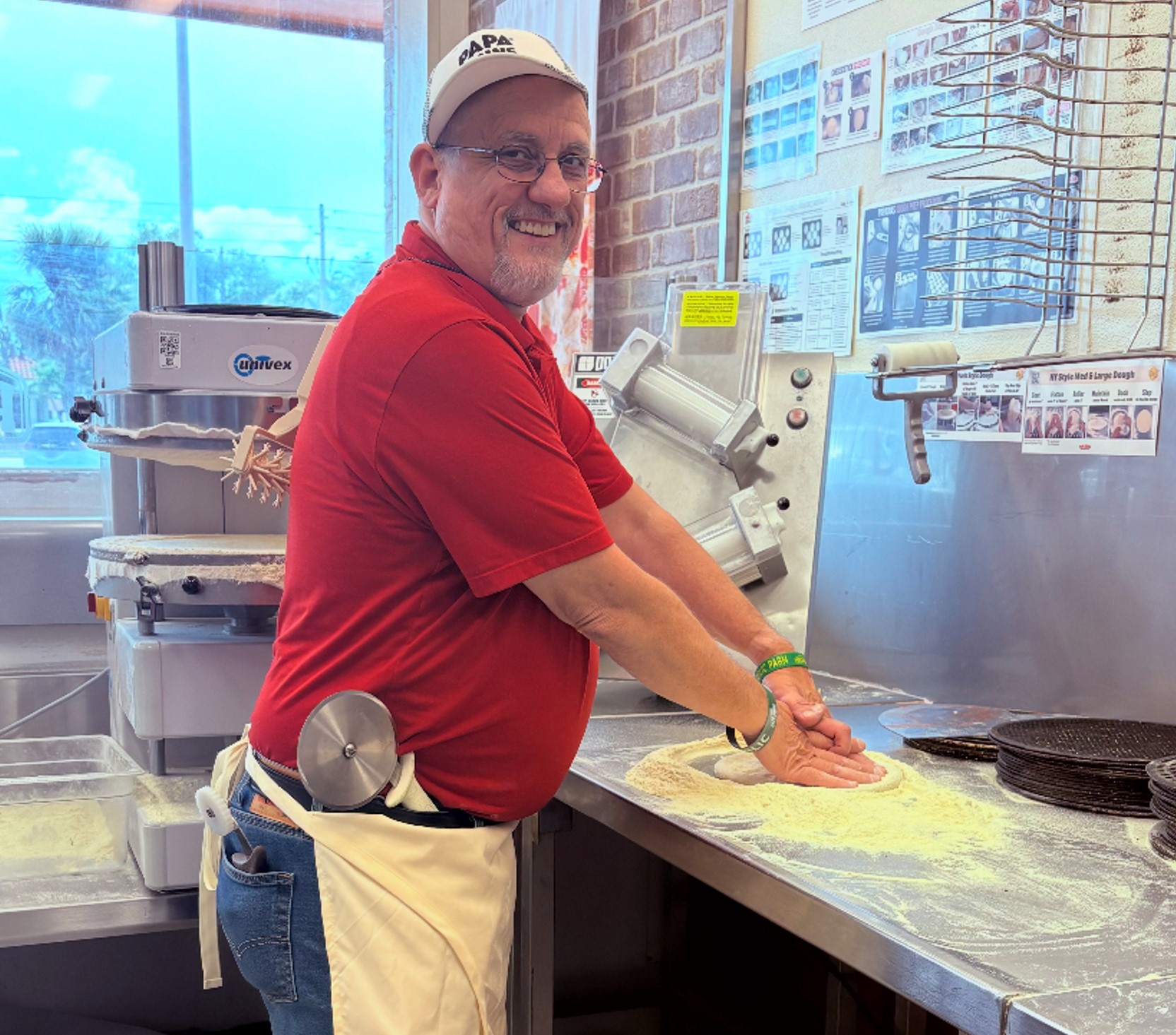 A man making a pizza inside a Papa Johns restaurant