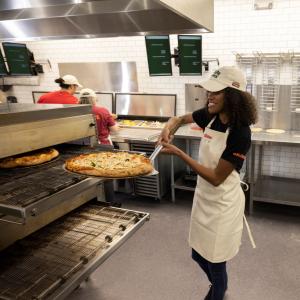 Papa Johns team member removing pizza from oven